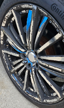 Damaged rim before repair — badly peeling and chipped black finish on a split-spoke wheel